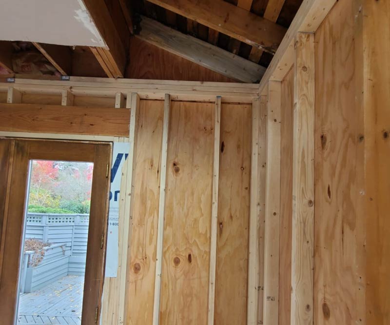 Professional reconstruction following water damage, showcasing new, clean wooden structural framing and moisture barriers installed by Final Touch Construction.