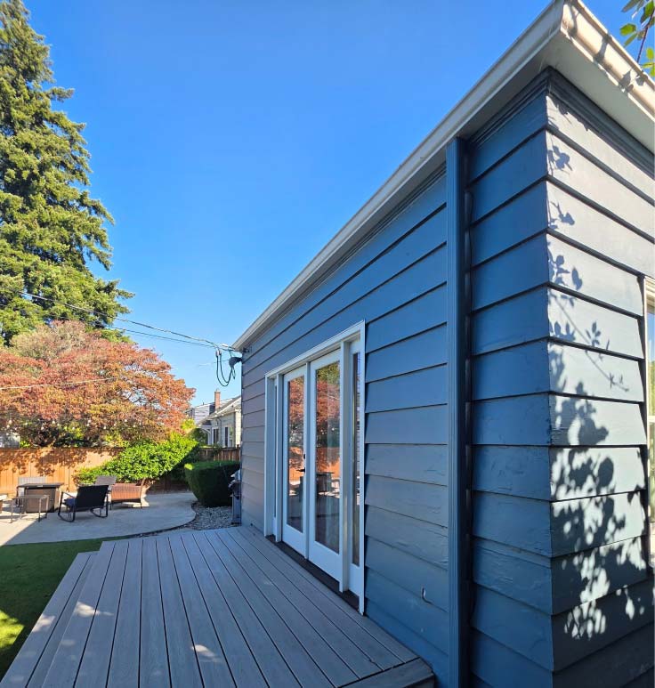 Clean roofline showing expert Fascia Repair and integrated gutter systems on a blue residential property with modern deck finishes.