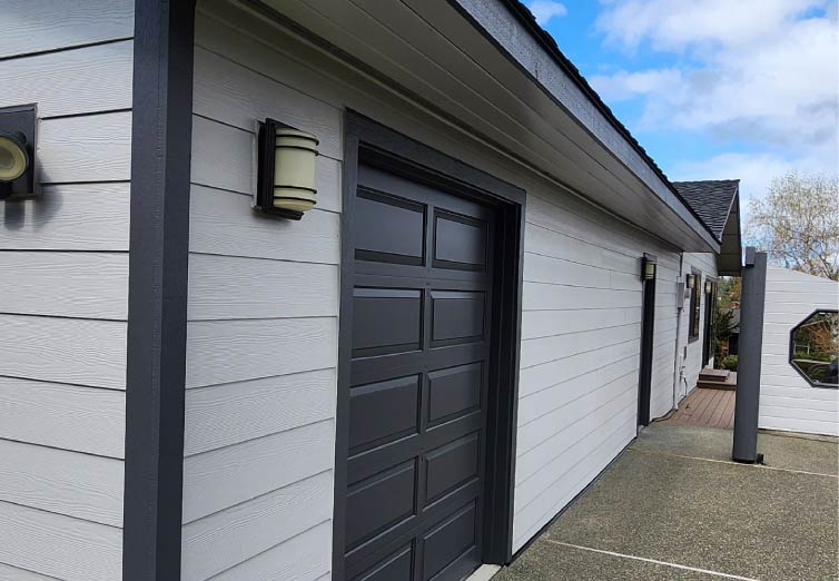Modern residential garage exterior featuring light grey horizontal lap siding with high-contrast black trim and designer lighting by Final Touch Roofing & Siding.