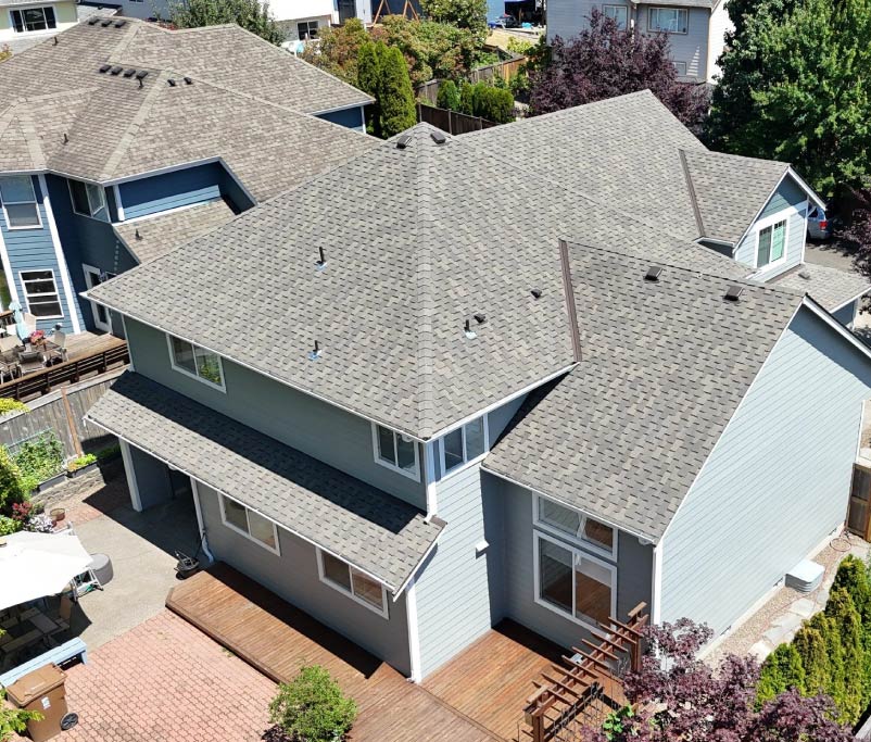 Aerial view of a recently completed multi-gable asphalt shingle roof in Seattle, showcasing uniform architectural shingles and professional ridge vent installation by Final Touch Roofing & Siding.