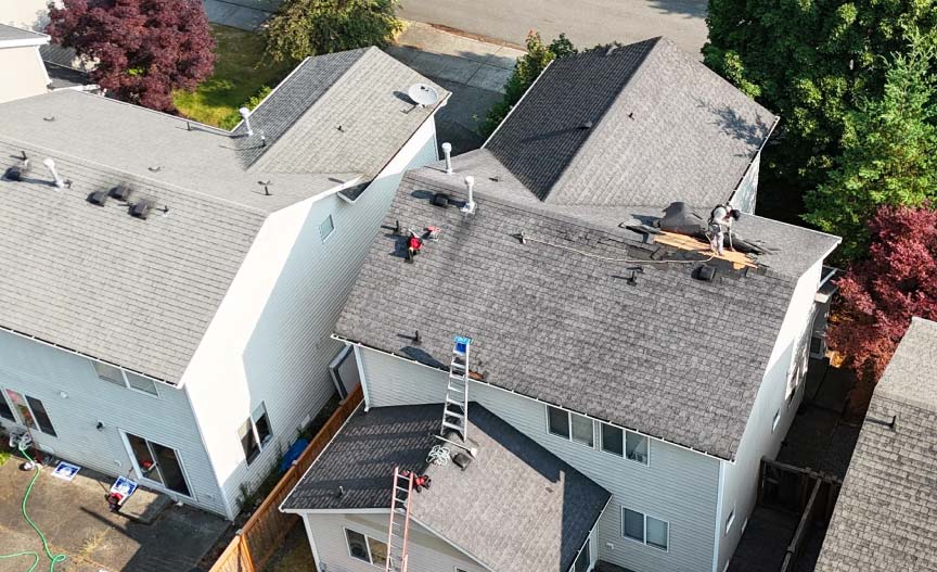 Professional roofing crew performing an emergency tarping and forensic damage assessment on a residential roof in Seattle.