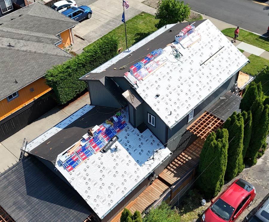 High-performance synthetic underlayment installation on a residential roof, featuring GAF-branded weather barriers and systematic shingle staging for maximum moisture protection.