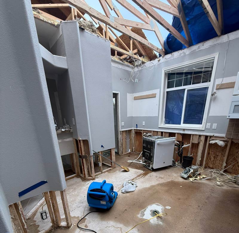 Interior view of a catastrophic home restoration project managed by Final Touch Construction, showing extensive structural drying and industrial air movers deployed after a major roof failure.