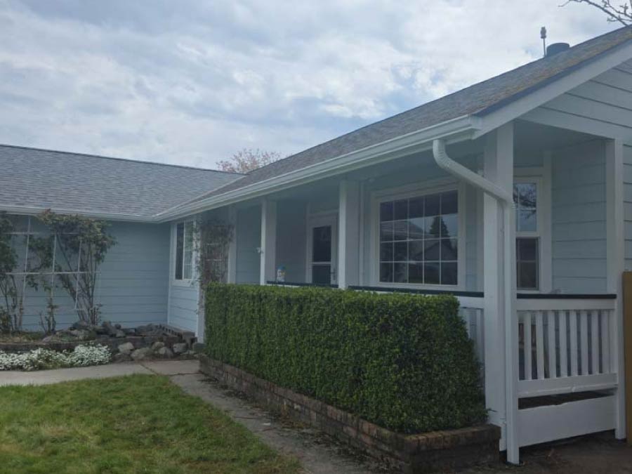 High-capacity white seamless gutters installed on a light blue residential property to ensure maximum water diversion from the foundation.