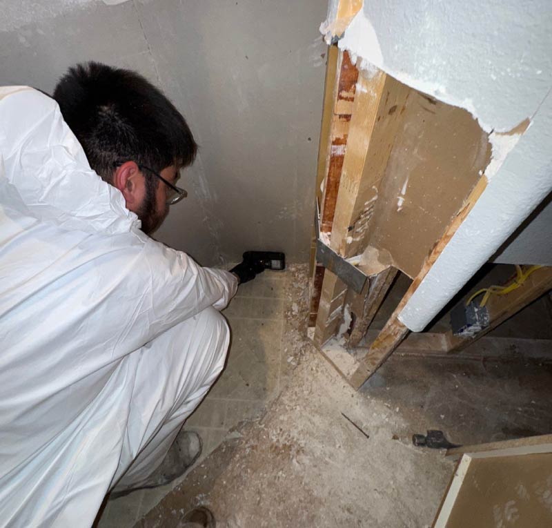 An IICRC-certified restoration technician from Final Touch Construction using a moisture meter to detect hidden water damage behind drywall during an emergency home mitigation project in Seattle.