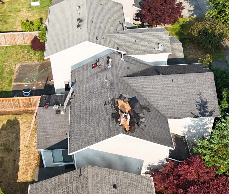 Aerial perspective of specialized technicians actively repairing compromised roof decking and structural framing following severe weather destruction.