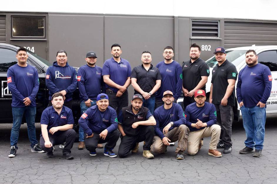 team-members Final Touch Construction LLC full team of roofing and siding specialists posing together in front of company banner at their Tukwila, Washington office, wearing branded navy uniforms with GAF certification patches