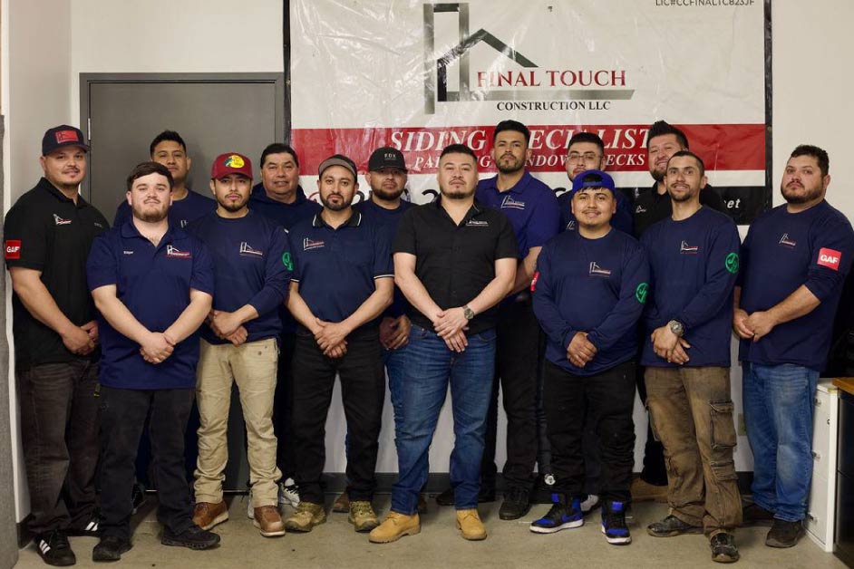 team-of-final-touch Final Touch Construction LLC full team of roofing and siding specialists posing together in front of company banner at their Tukwila, Washington office, wearing branded navy uniforms with GAF certification patches