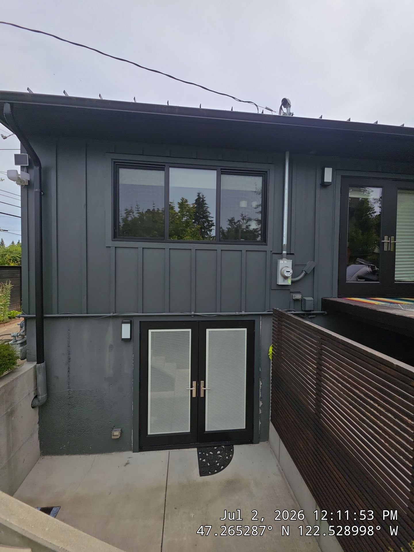 Close-up exterior view of a home's corner showcasing newly exterior painting painted gray horizontal lap siding accented by clean white vertical trim and a white door frame.